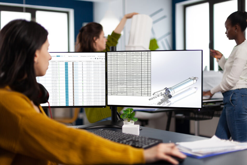 Industrial engineer woman working at pc with two monitors, screens showing CAD software with 3D architecture prototype of gears mechanical piece. Entrepreneur working in creative construction office